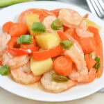 A sheet pan meal featuring succulent shrimp, crisp carrots, and crunchy celery on a white plate.