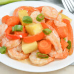 A sheet pan meal featuring succulent shrimp, crisp carrots, and crunchy celery on a white plate.