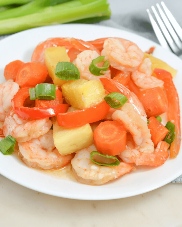 A sheet pan meal featuring succulent shrimp, crisp carrots, and crunchy celery on a white plate.