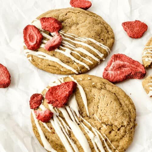 A plate of strawberry cheesecake cookies with icing on it.
