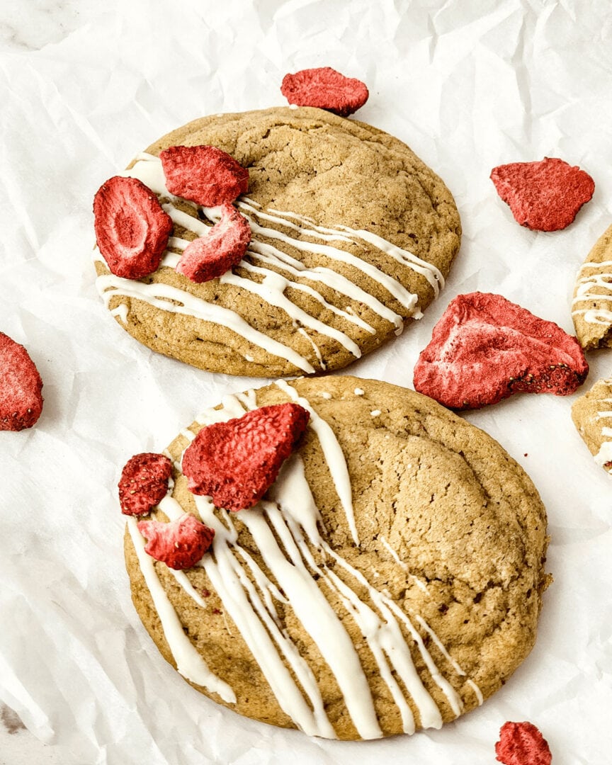 A plate of strawberry cheesecake cookies with icing on it.
