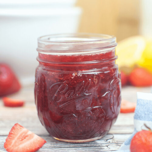 Strawberry jam without pectin in a jar on a wooden table.