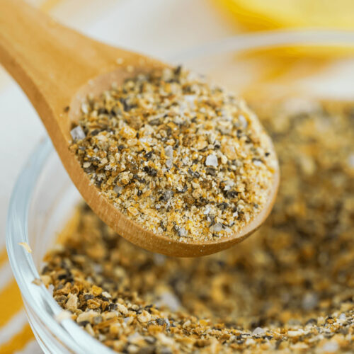 A wooden spoon filled with a salt and pepper mixture, a substitute for Lemon Pepper Seasoning.