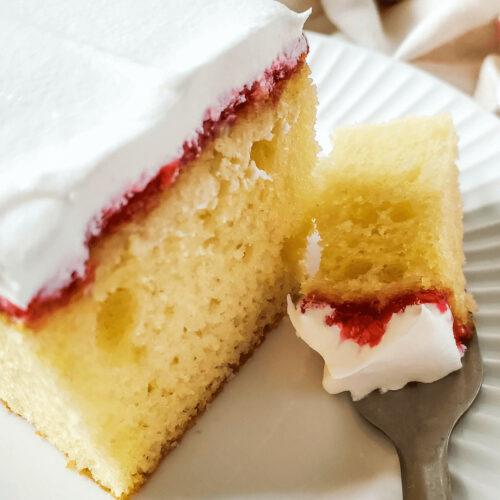 A slice of vanilla raspberry cake on a plate with a fork.