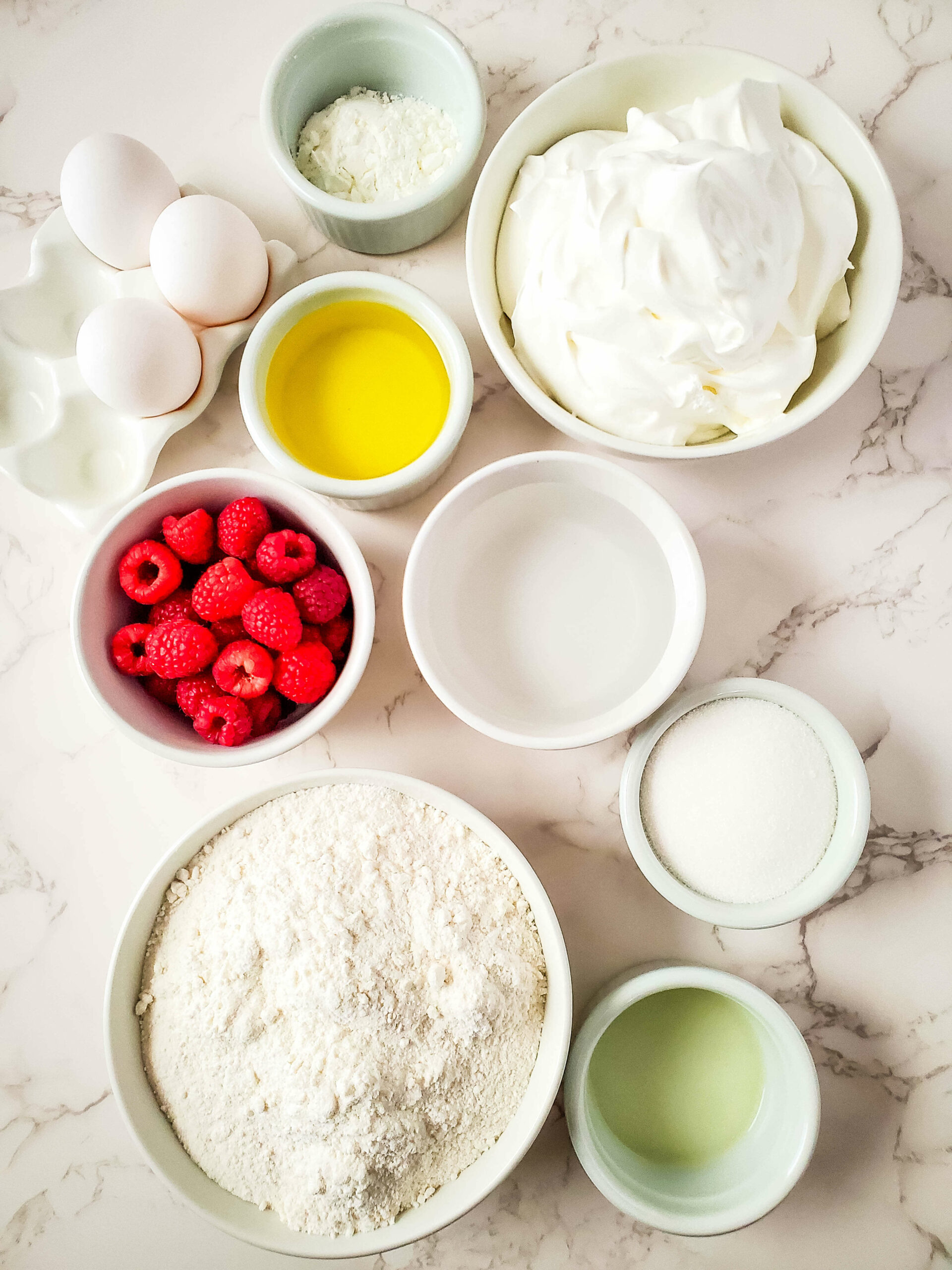 A bowl of ingredients for a vanilla raspberry cake with whipped cream.