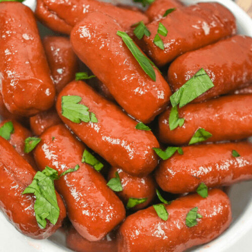 Sausages in a white bowl with parsley.