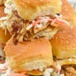 A close-up of stacked BBQ Chicken Sliders with coleslaw and cheese on soft, golden buns.
