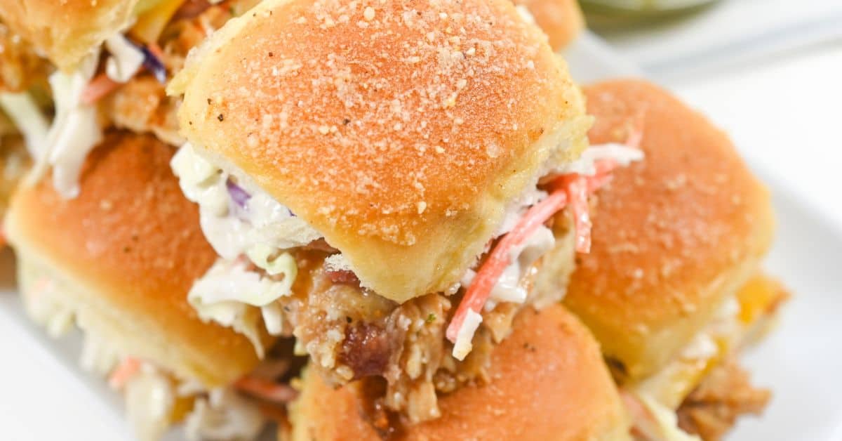 Close-up of BBQ Chicken Sliders on soft buns filled with fried chicken and coleslaw, arranged on a white plate.