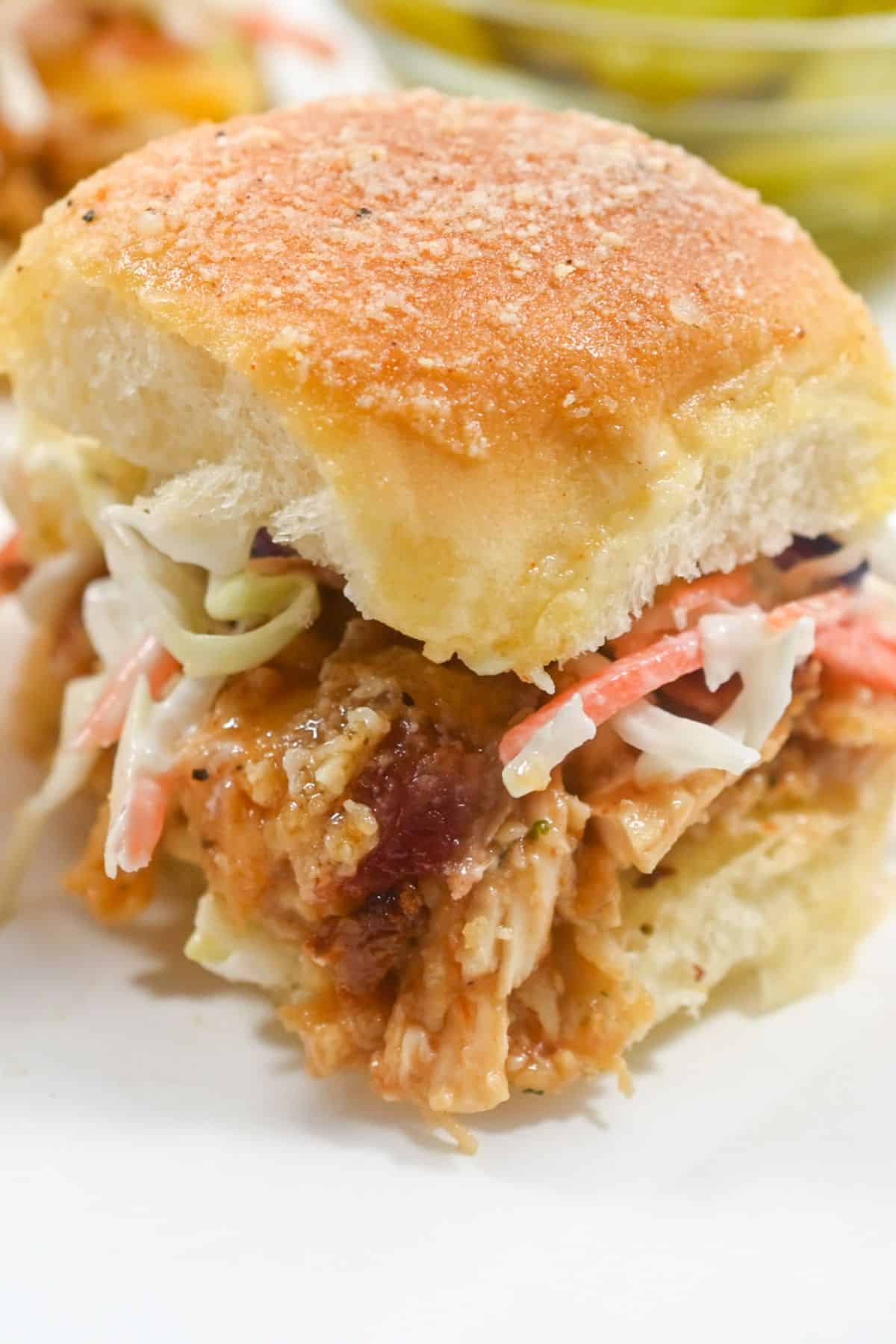 A close-up of a sandwich on a soft, golden bun sits on a white plate.