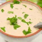 A bowl with Baja Chipotle Sauce and lime wedges in the background.