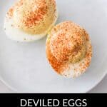 Two deviled egg halves topped with paprika sit on a white plate, perfectly showcasing Deviled Eggs without Mayonnaise. Text below reads "Deviled Eggs Without Mayonnaise.