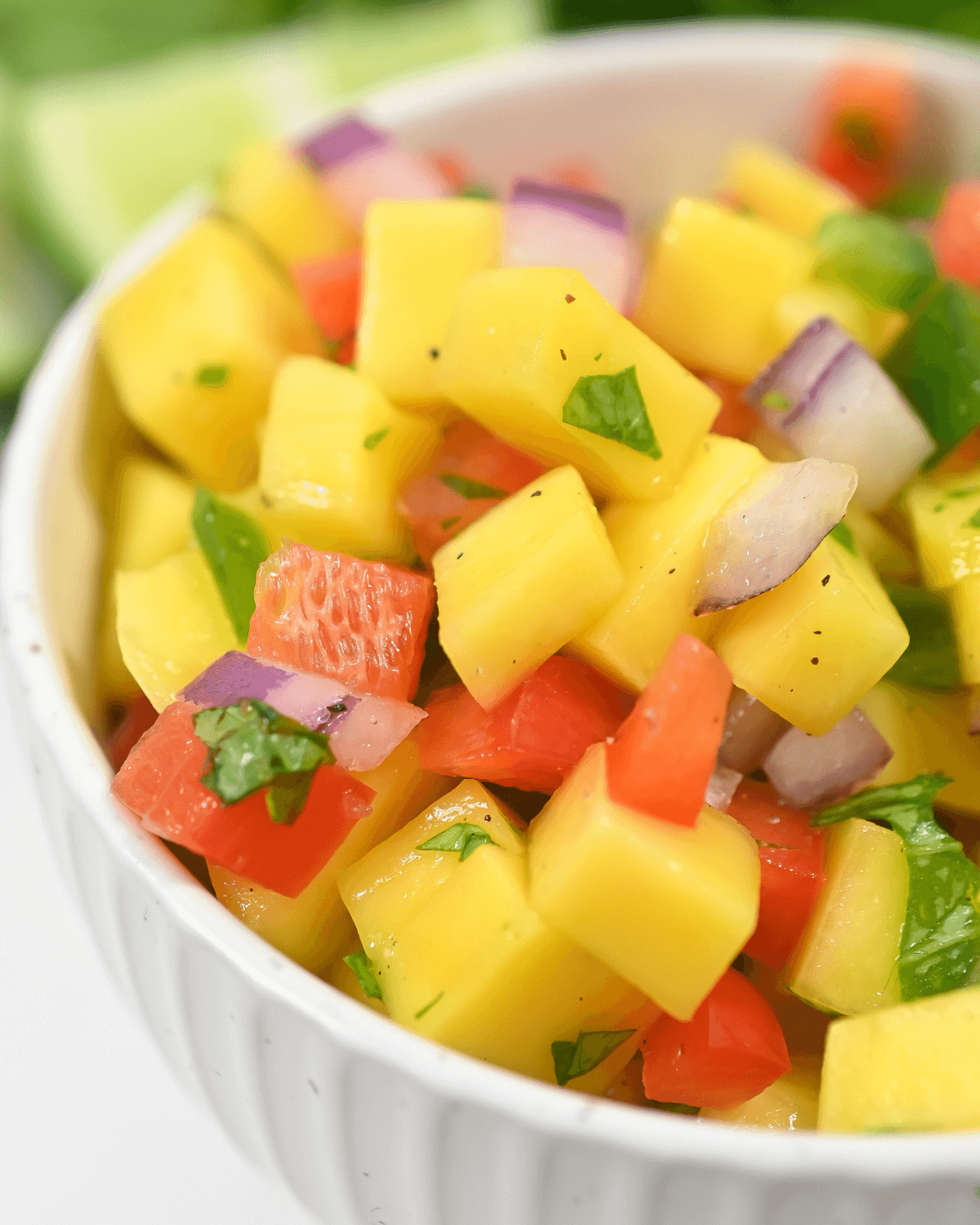 A colorful bowl of fresh mango habanero salsa with red onion and herbs.