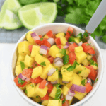 A bowl of mango habanero salsa garnished with lime and cilantro.