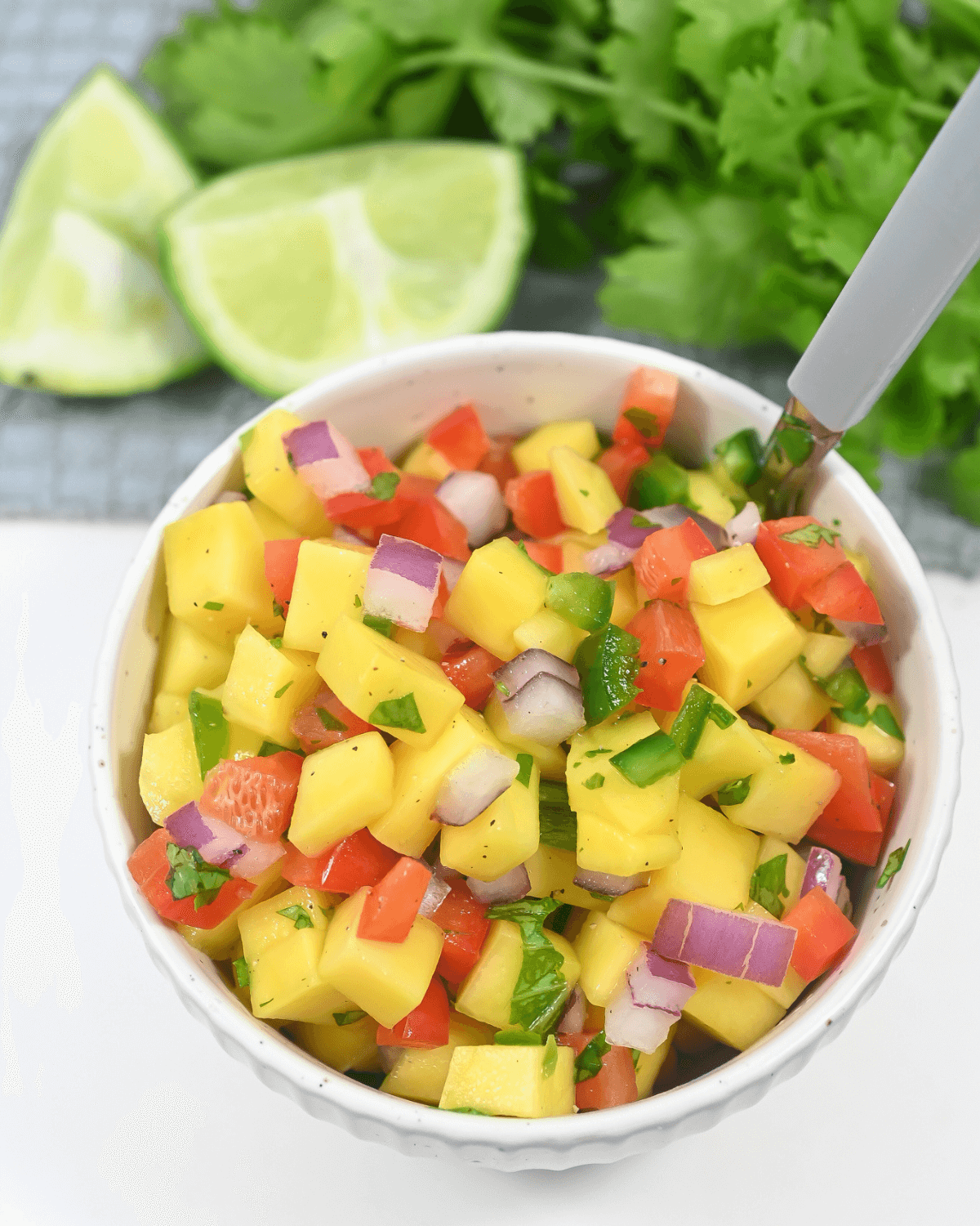 A bowl of mango habanero salsa garnished with lime and cilantro.