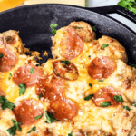 Cheesy tomato-topped cooked in a skillet, garnished with herbs and served as a pizza dip.