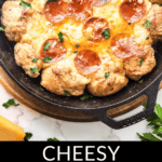 Pepperoni and cheese pizza dip with bread rolls served in a cast iron skillet.