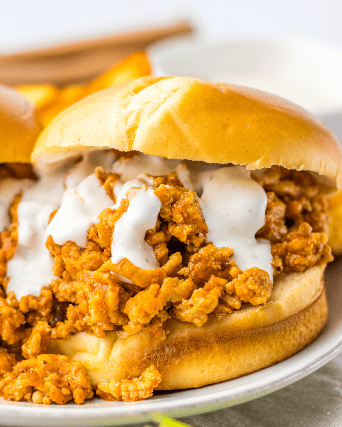 A buffalo chicken sloppy joe sandwich with ground meat and sauce on a bun, made in a slow cooker.