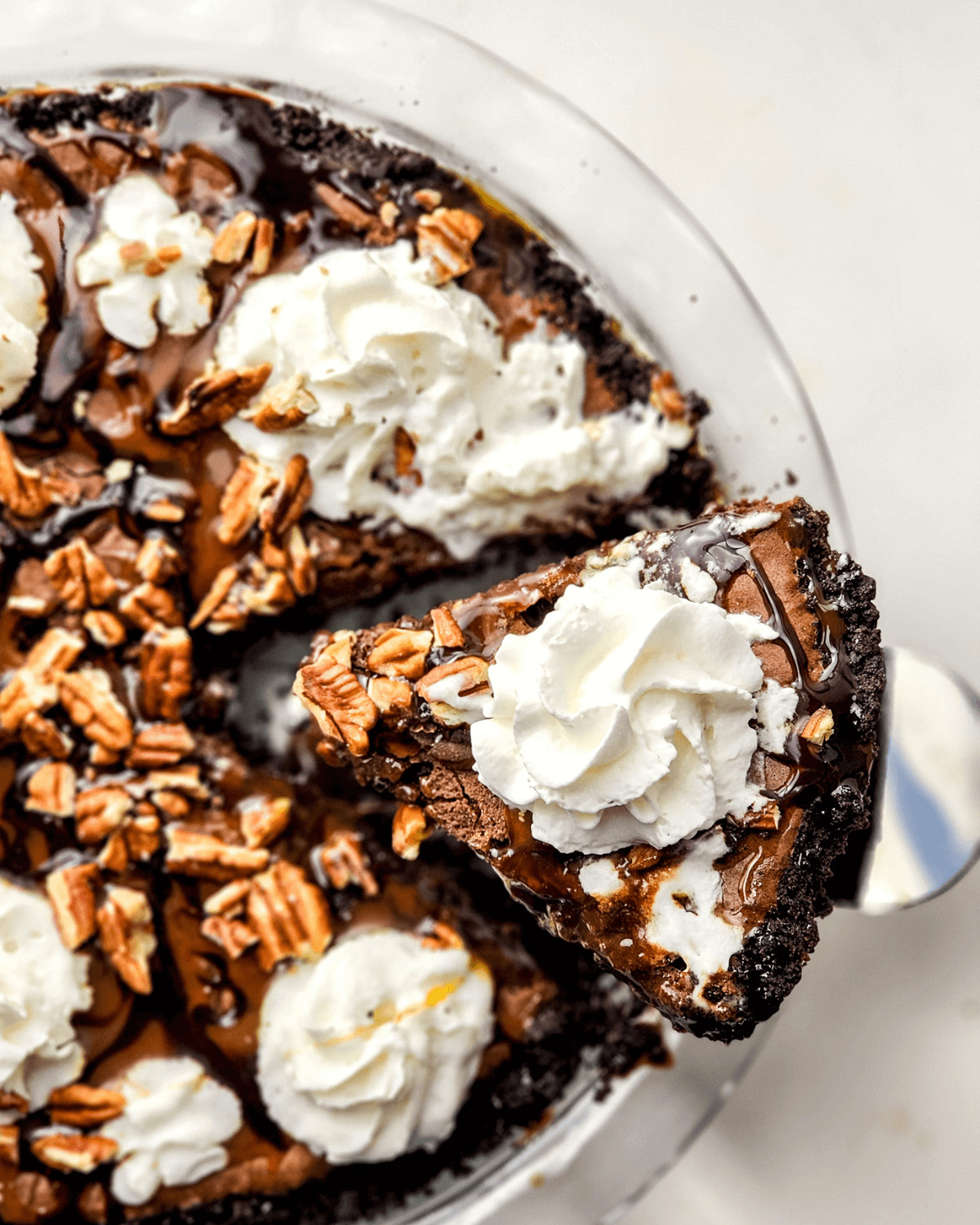 A slice of brownie pie with whipped cream and pecans on top.
