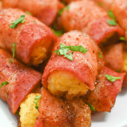 Bacon wrapped cornbread bites on a white plate.