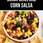 A bowl of Black Bean and Corn Salsa with diced tomatoes, red onion, and cilantro is surrounded by crispy tortilla chips on a plate.