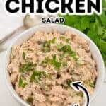 A bowl of chipotle chicken salad topped with chopped herbs is shown on a white surface, with a spoon and fresh cilantro in the background. Text reads “Chipotle Chicken Salad Spicy,” highlighting the bold flavors of this classic chipotle chicken salad.