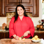 Woman in red blouse slicing lemons in a kitchen setting.