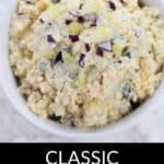 A white bowl filled with Classic Egg Salad, topped with chopped red onions, sits on a white surface. The text "CLASSIC EGG SALAD" appears below the bowl.