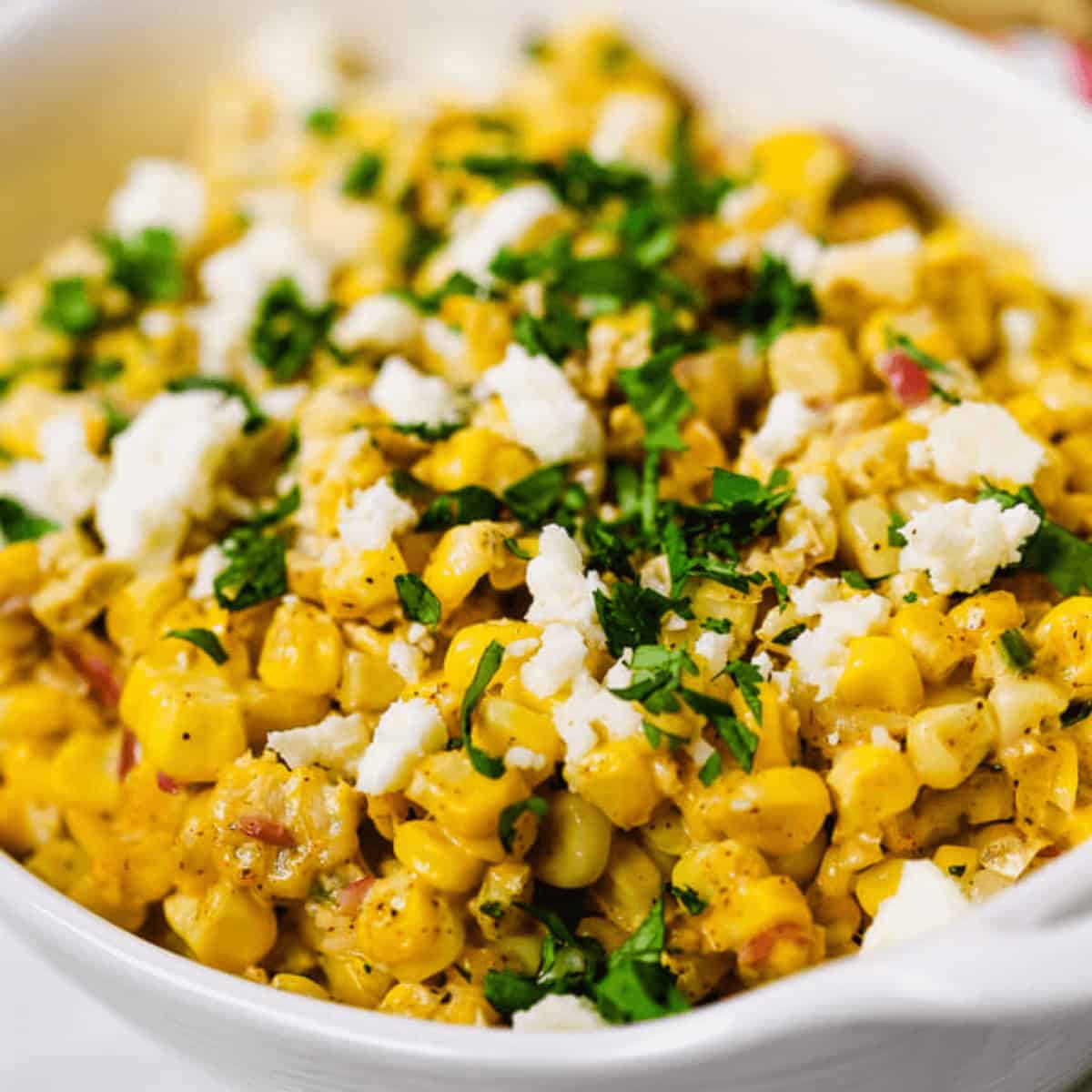 A bowl of Elote Salad, Mexican street corn salad topped with crumbled cheese and chopped cilantro.