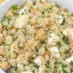 A bowl of Jennifer Aniston salad with quinoa, chickpeas, cucumber, feta cheese, and herbs, garnished with lemon slices.