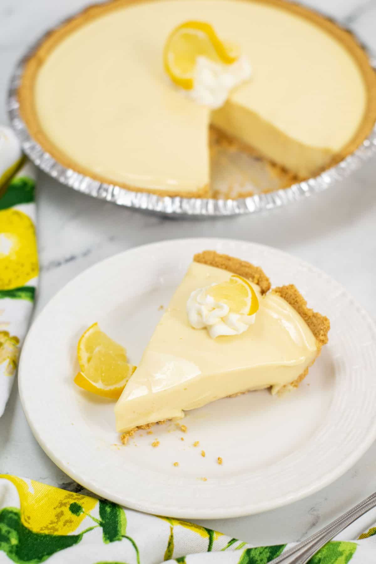 A slice served on a white plate; the rest of the pie is in the background with one slice missing.