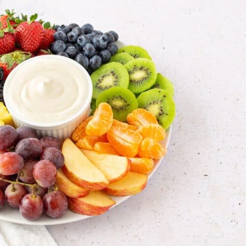 A plate with strawberries, blackberries, blueberries, kiwi slices, pineapple, grapes, mandarin orange segments, apple slices, and a bowl of Marshmallow Fluff Fruit Dip in the center.