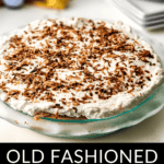 An old-fashioned coconut cream pie topped with whipped cream and toasted coconut flakes, served on a glass plate with a blurred background.