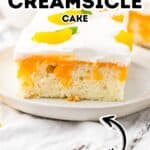 A slice of Orange Creamsicle Cake with white frosting and orange pieces sits on a white plate; text overlay reads "Orange Creamsicle Cake Easy.