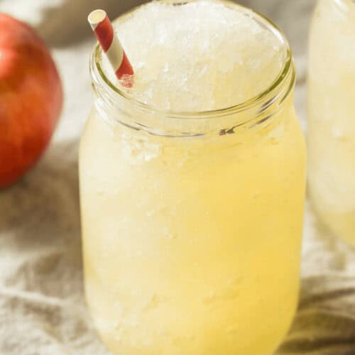 A mason jar filled with Apple Cider Slush, topped with a red and white striped straw.