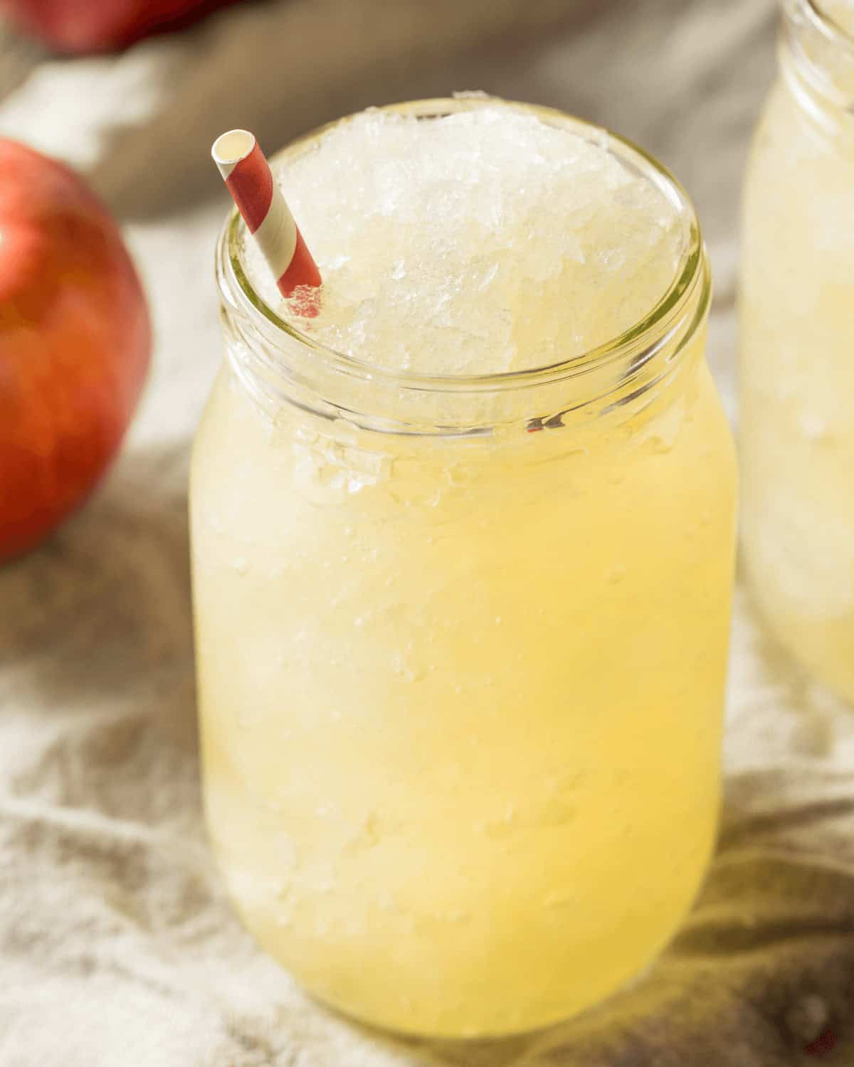 A mason jar filled with Apple Cider Slush, topped with a red and white striped straw.