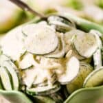 Bowl mixed with a creamy dressing, sprinkled with dill, and served with a spoon in the bowl.