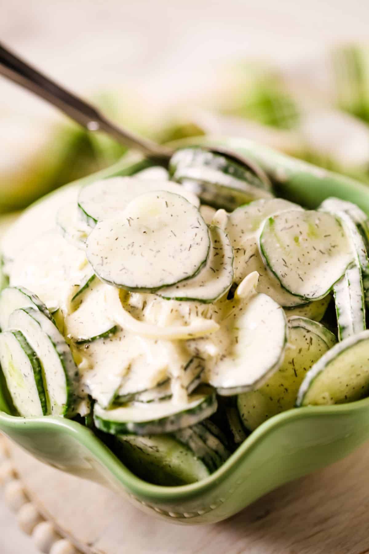Bowl mixed with a creamy dressing, sprinkled with dill, and served with a spoon in the bowl.