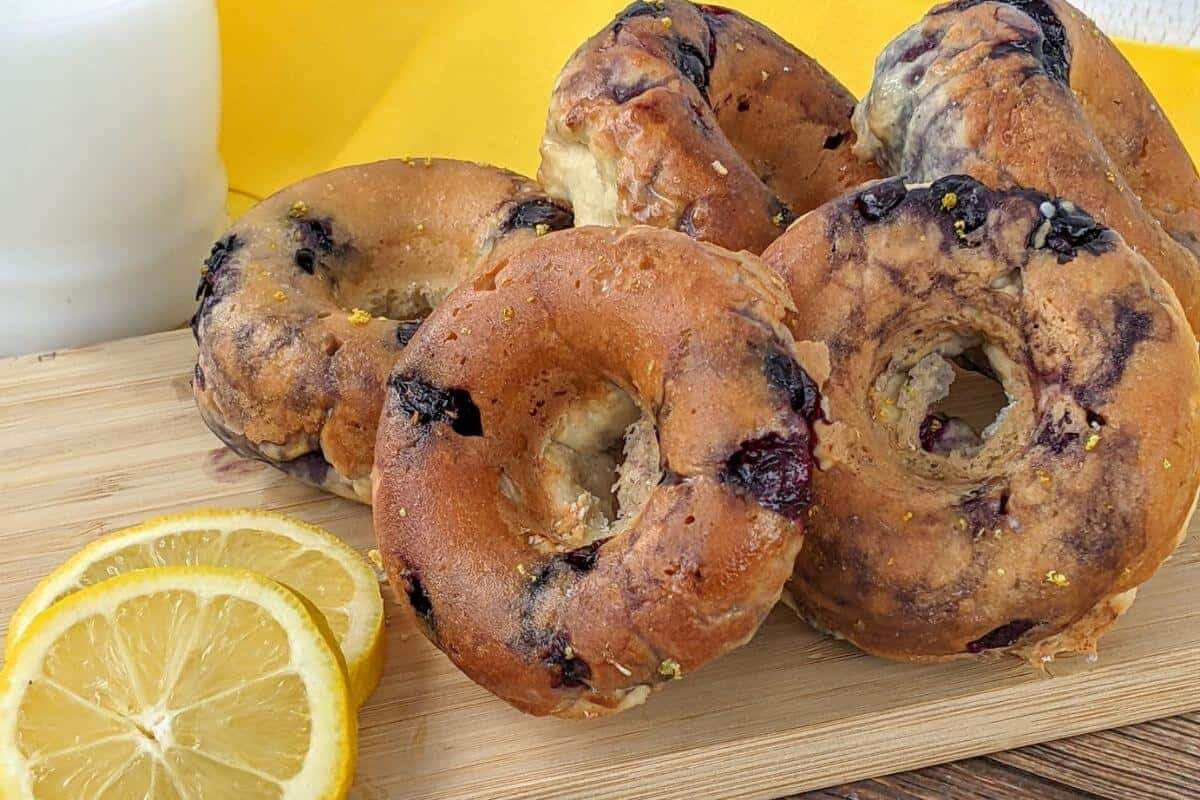 Blueberry glazed donuts on a wooden board with lemon slices. 