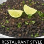 A bowl of Mexican black beans garnished with lime wedges and chopped cilantro, labeled "restaurant-style Mexican black beans.