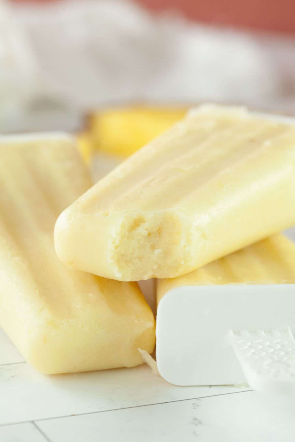 Three frozen desserts are stacked on a white surface, with one showing a bite taken out of it.