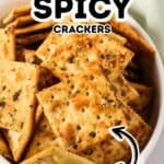 A white dish filled with square, seasoned ranch spicy crackers, with text overlay reading "Ranch Spicy Crackers Bold." Try this easy Spicy Crackers Recipe for a flavorful snack!.