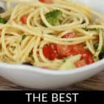 A bowl of spaghetti pasta salad with tomatoes, broccoli, and other fresh vegetables. The text at the bottom reads "The Best Spaghetti Pasta Salad".