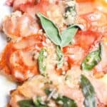 A plate of saltimbocca, featuring slices of chicken topped with prosciutto, fresh sage leaves, and a light sauce, reminiscent of the classic veal saltimbocca.