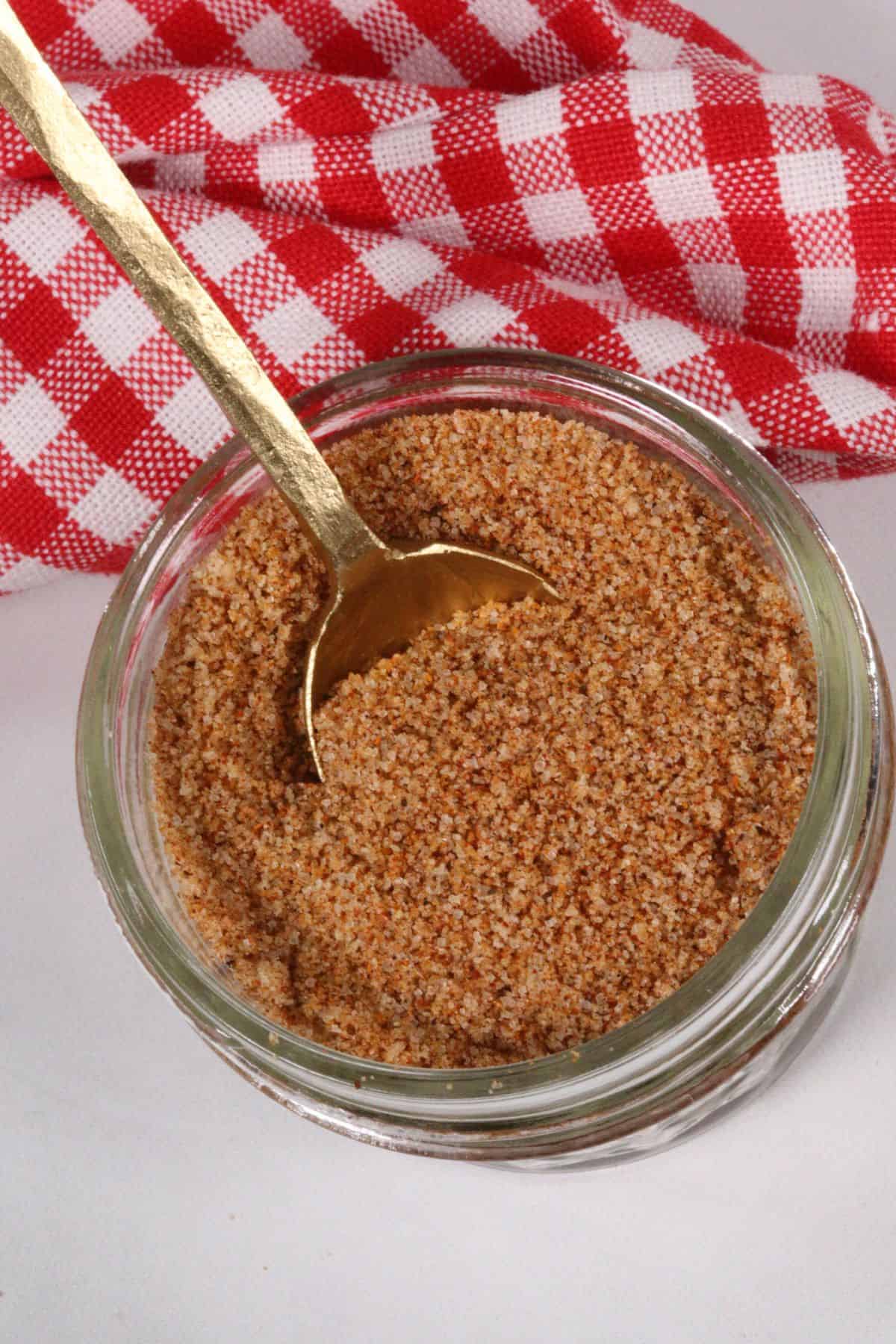 A jar of the best bbq spice rub on a checkered napkin.