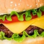 Close-up of a delicious Baked Hamburger with lettuce, tomato, cheddar cheese, and a beef patty in a sesame seed bun.