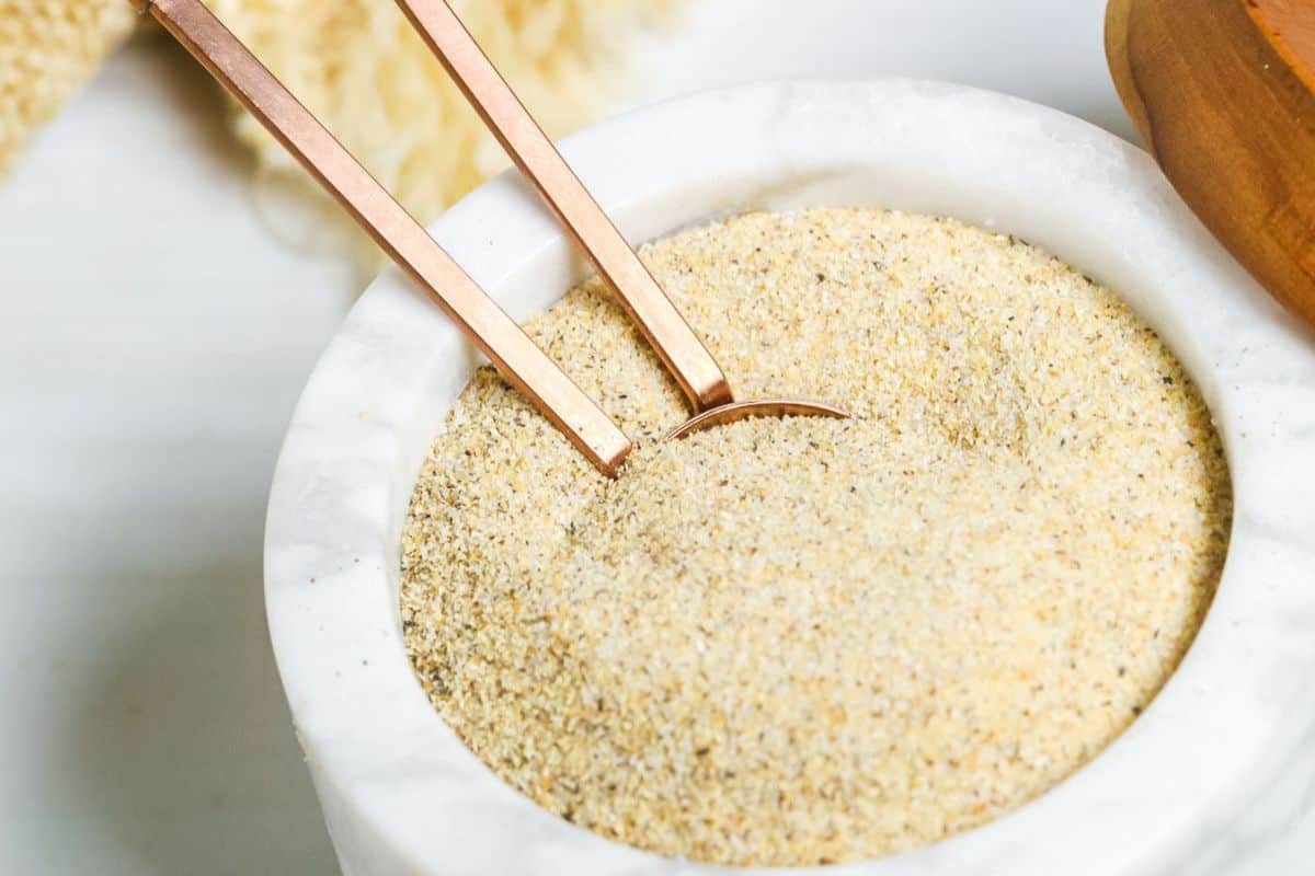 White bowl of yellow all-purpose seasoning with a spoon going into it. 