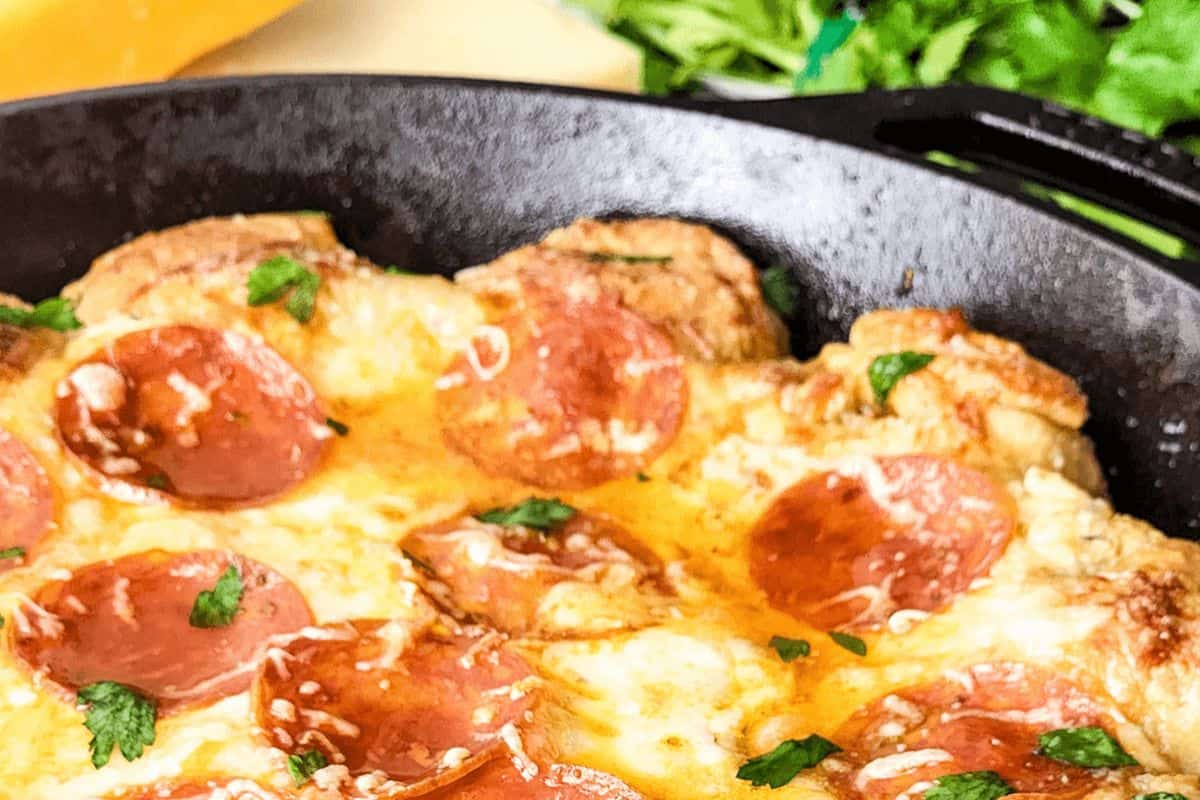 Cast-iron pan full of pizza dipped topped with pepperoni. 