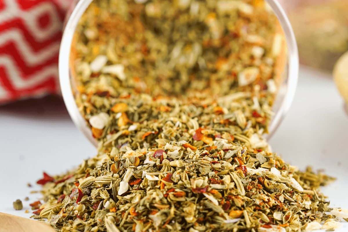 Multi-color pizza seasoning pouring out of glass jar. 