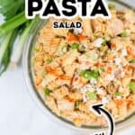 A bowl of spicy buffalo chicken pasta salad with rotini noodles, crumbled cheese, chopped green onions, and parsley, labeled as "Chicken Pasta Salad" and "Spicy.