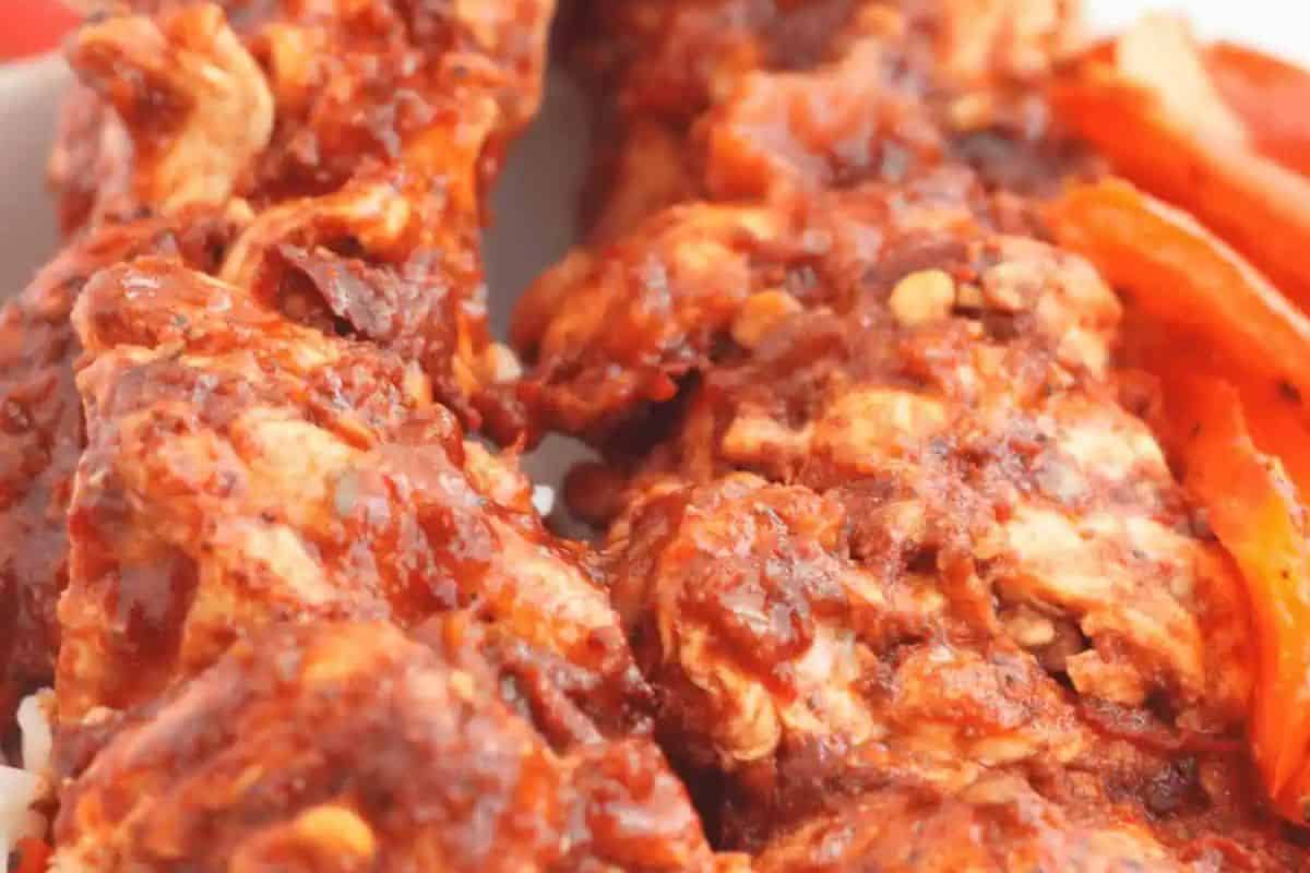 Close-up of grilled chicken skewers coated in a red, spicy marinade, with visible seasoning and slices of red bell pepper—perfect inspiration for your next kabob recipes.